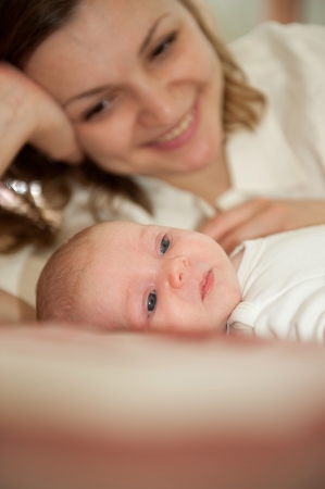 Young mother is lying with her little baby daughterの写真素材