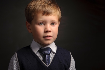 Cute pupil portrait against dark classroom blackboard