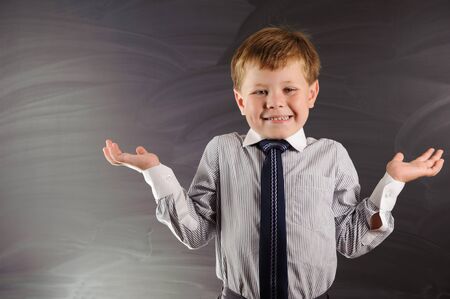 Cute preschooler against dark blackboard in classroom
