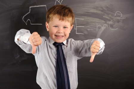 Cute preschooler against dark blackboard in classroomの写真素材