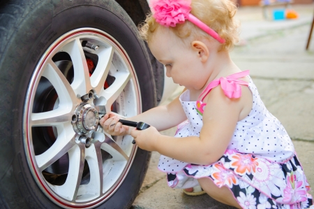 Cute girl with head band repairing alloy wheel of a real carの写真素材