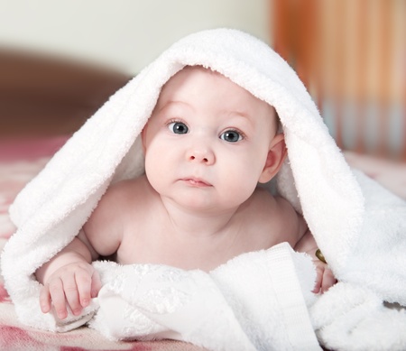 Cute little baby lying under white towelの写真素材