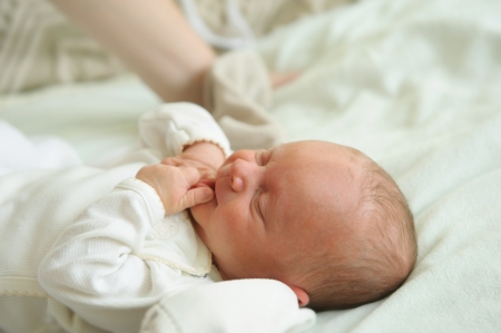 Beautiful newborn baby lying in his bedの写真素材