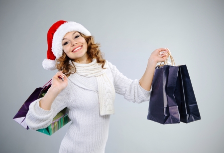 Beautiful young girl in red Santa hat with shopping bagsの写真素材