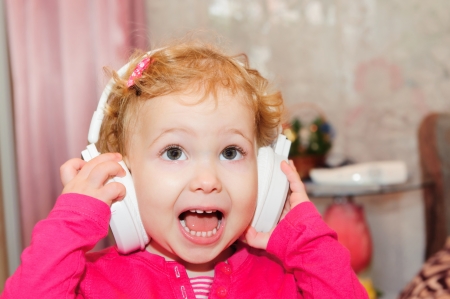 Cute little girl enjoying music using headphonesの写真素材