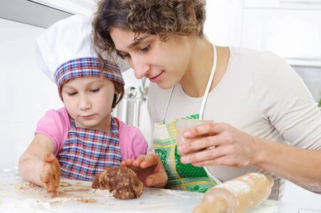 Young mother with little daughter shaping cookiesの写真素材