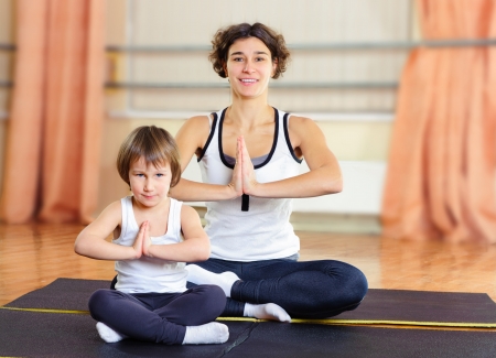 Young mother with little daughter exercising in gymの写真素材