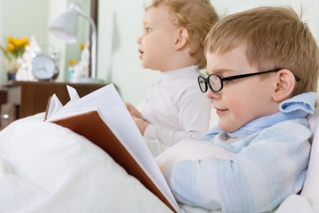 Little girl and her sick brother lying in bed at homeの写真素材