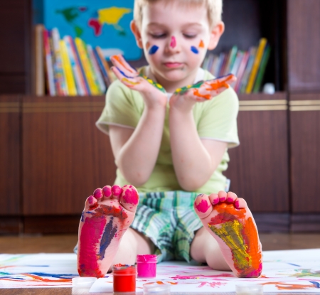 Cute happy boy with colorful  painted hands and footの写真素材
