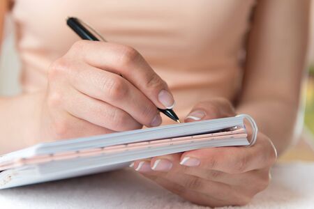 Young female is writing notes and planning her scheduleの写真素材