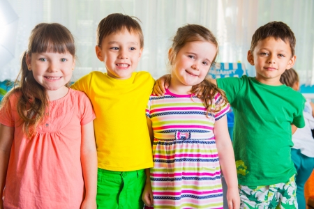Group of four hapy preschoolers standing in playroomの写真素材