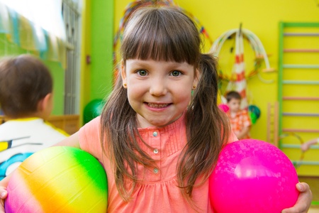 Cute little girl playing at daycare gym with ballの写真素材