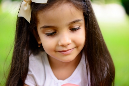 Portrait of hispanic girl with deep blue eyes in sunny parkの写真素材