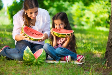 Happy hispanic family eating watermelon at parkの写真素材