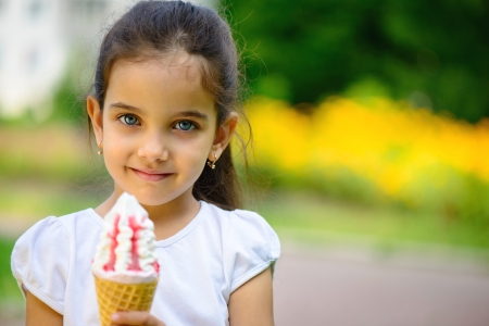 Cute hispanic little girl with ice-cream at parkの写真素材
