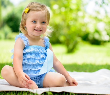 Cute smiling little girl sitting on grassの写真素材
