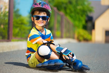 Cute little boy in sunglasses and helmet with rollersの写真素材