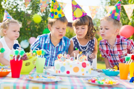 Kids celebrating birthday party and blowing candles on cakeの写真素材