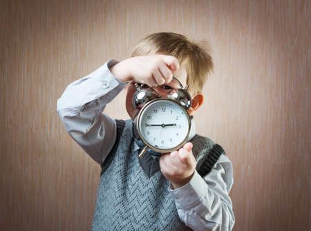 Portrait of cute diligent boy holding alarm clock