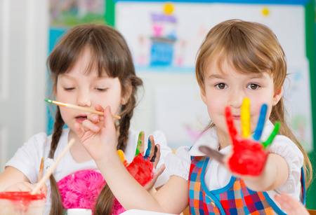 Cute preschool children painting with their palms at kindergartenの写真素材