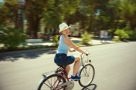 Happy young girl with bicycle in townの写真素材
