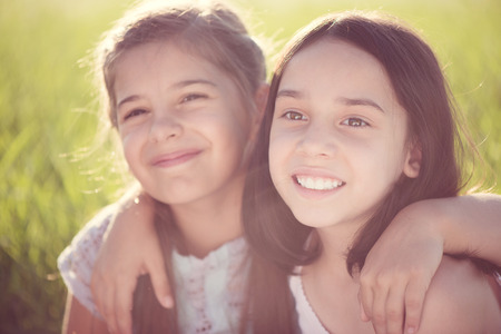 Portrait of two hispanic teens girls resting on meadowの写真素材