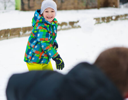 Children throwing snowballs in snowy winter parkの写真素材