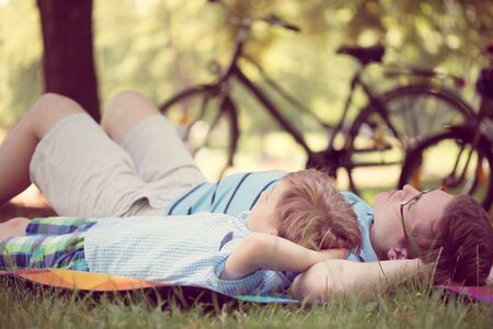 Young father with little sun dreaming at summer parkの写真素材