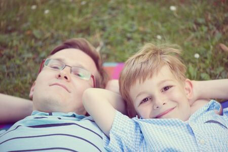 Young father with little sun dreaming at summer park