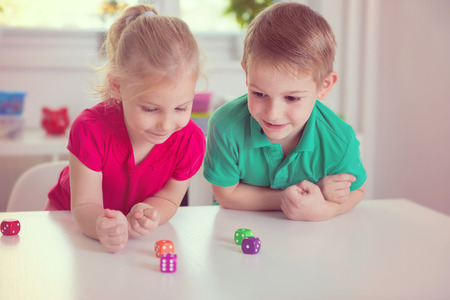 Two happy children playing with dices at home Two happy children playing with dices at home