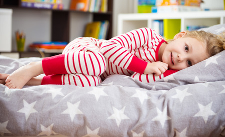 Cute little girl in pajama sleeping in bedの写真素材