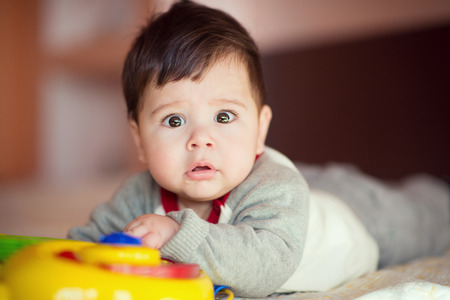 Portrait of happy beautiful baby on the bed in his room.の写真素材
