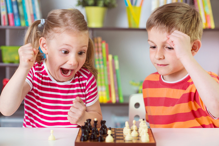 Two cute children playing chess at homeの写真素材