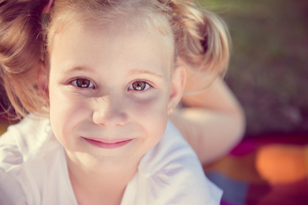 Excited face of pretty small girl in summer parkの写真素材