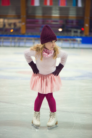 Pretty little girl skates in a red cap, warm gloves and sweaterの写真素材