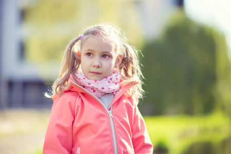 Portrait of pretty small school girl in sunny parkの写真素材