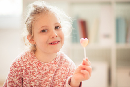 Portrait of pretty happy child girl with lolipop in her handの写真素材