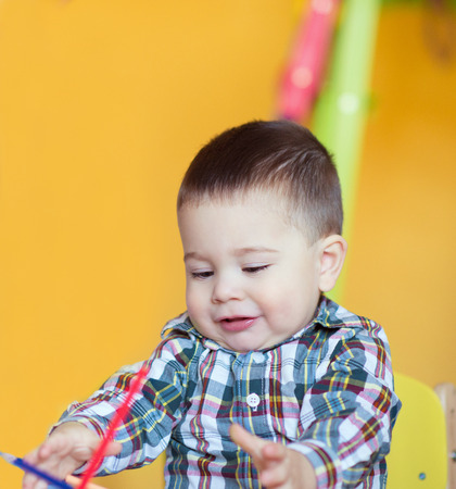 Cute little baby boy drawing with colorful pencils at the tableの写真素材