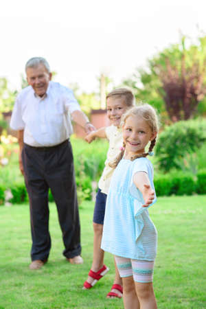 Portrait of happy old grandfather and cute children in summerの写真素材