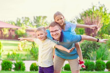 Portrait of happy father and two cute children playing at home  courtyardの写真素材