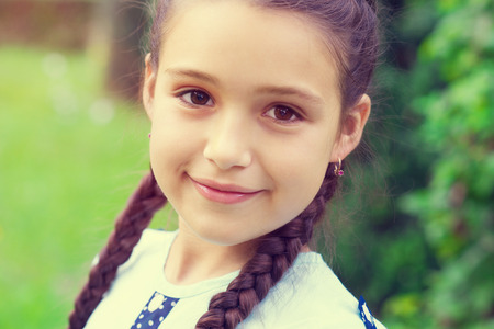 Portrait of pretty young girl with pigtails at sunny day in parkの写真素材
