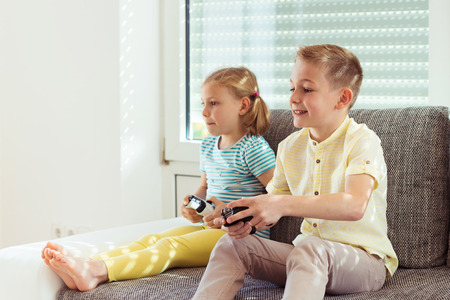 Two happy children playing video games with console at homeの写真素材