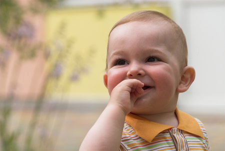 Cute little boy is looking up with fingers in his mouthの写真素材