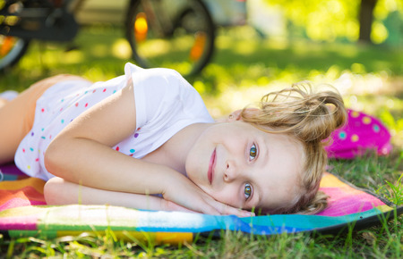 Excited face of pretty small girl in summer parkの写真素材