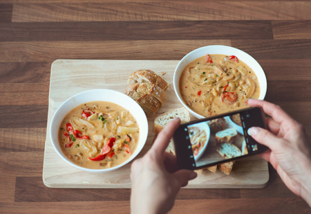 Closeup how womans hands photographing a vegetarian dish at health food restaurantの写真素材