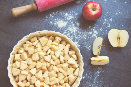 Traditional homemade apple pie and ingredients such as apple and cinnamon on wooden background for autumn holidayの写真素材