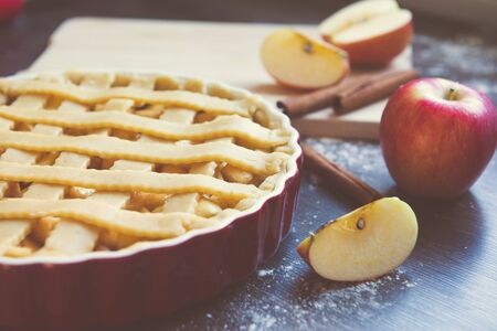 Traditional homemade apple pie and ingredients such as apple and cinnamon on wooden background for autumn holidayの写真素材