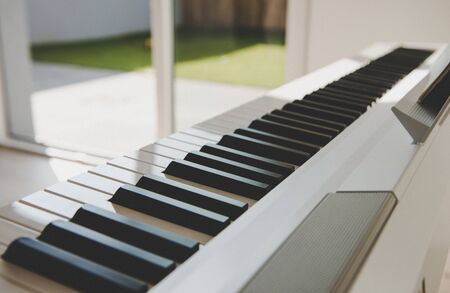 Closeup photo of electronic white piano at cosy homeの写真素材