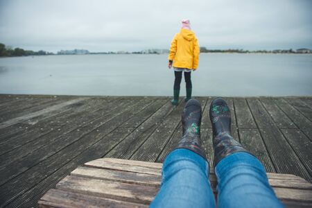 Teen brother and sister relaxing on a wooden pier in northern Germany