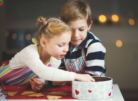 Happy little siblings children preparing Christmas cookies at homeの写真素材